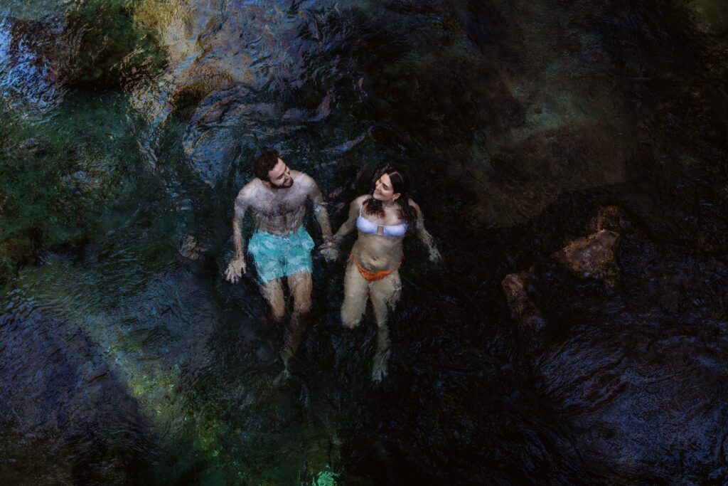 a couple swims in a river during their engagement session