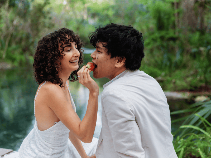 a girl feeds her partner a strawberry