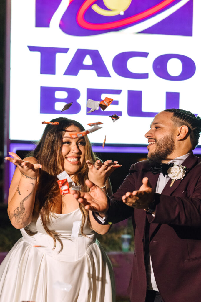 A couple eloped in Florida and celebrates their unique love story outside Taco Bell, joyfully tossing sauce packets in the air and sharing a fun, memorable moment.