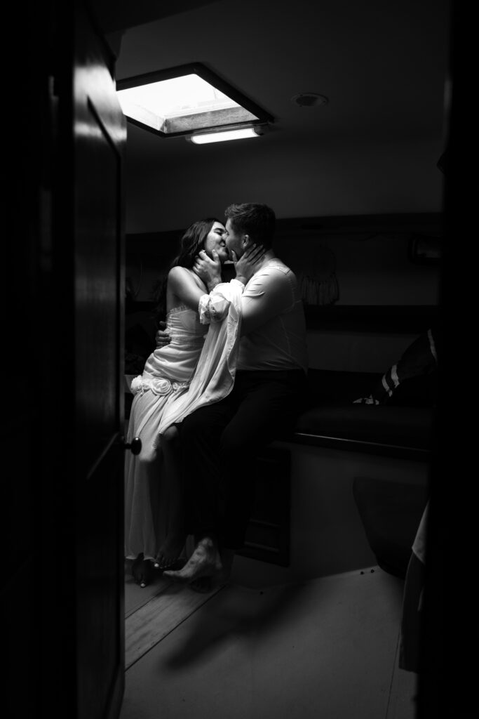 A couple eloped in Florida and shares an intimate kiss inside a cozy boat cabin, surrounded by soft lighting and a romantic atmosphere.