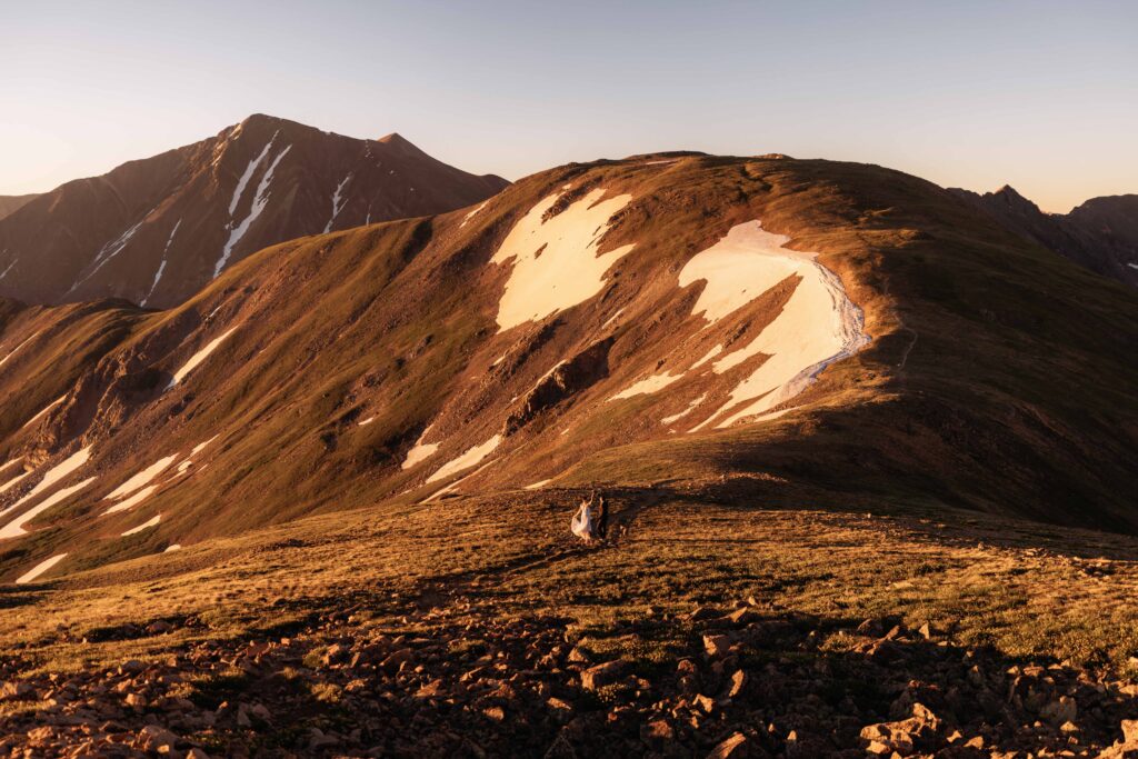 a couple wanders down a mountainside at sunrise for their elopement near Breckenridge, Colorado