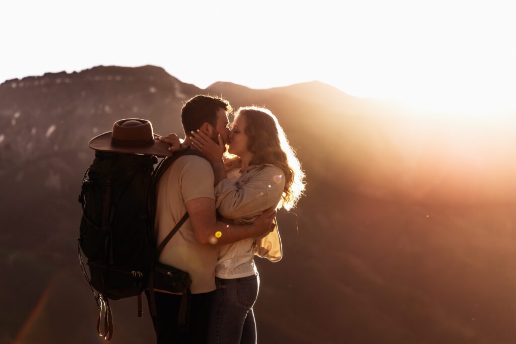 a couple kisses on top of a mountain at sunrise after hiking - colorado elopement guide