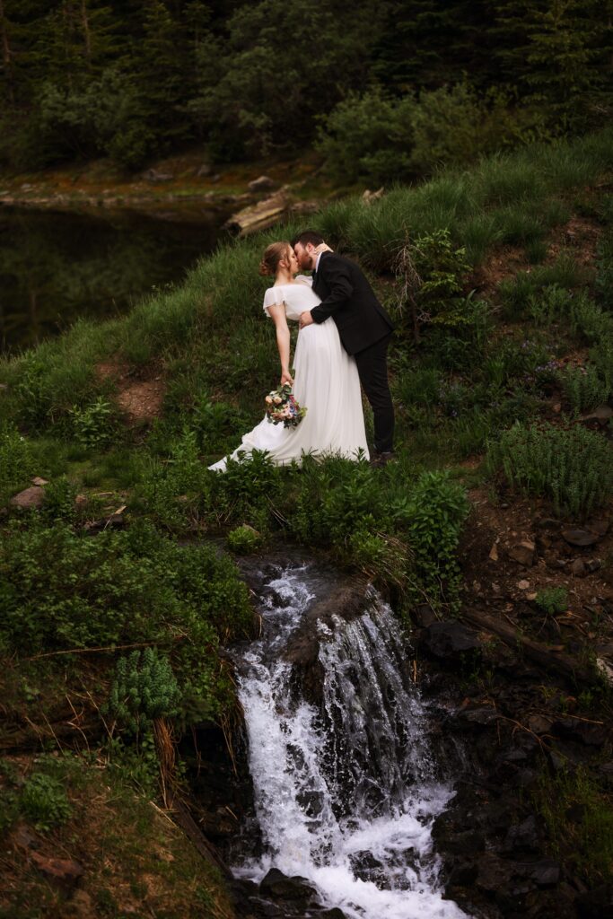 A couple kisses by a waterfall during their colorado elopement