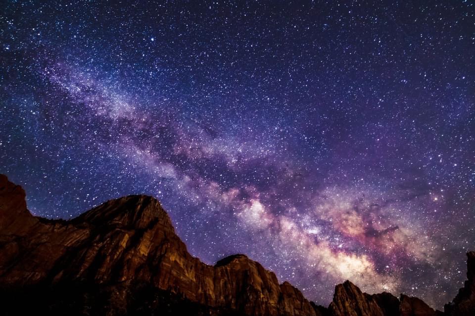 Starry night sky and Milky Way glowing above the cliffs of Zion National Park, a magical national park to elope for couples who love desert beauty and stargazing.