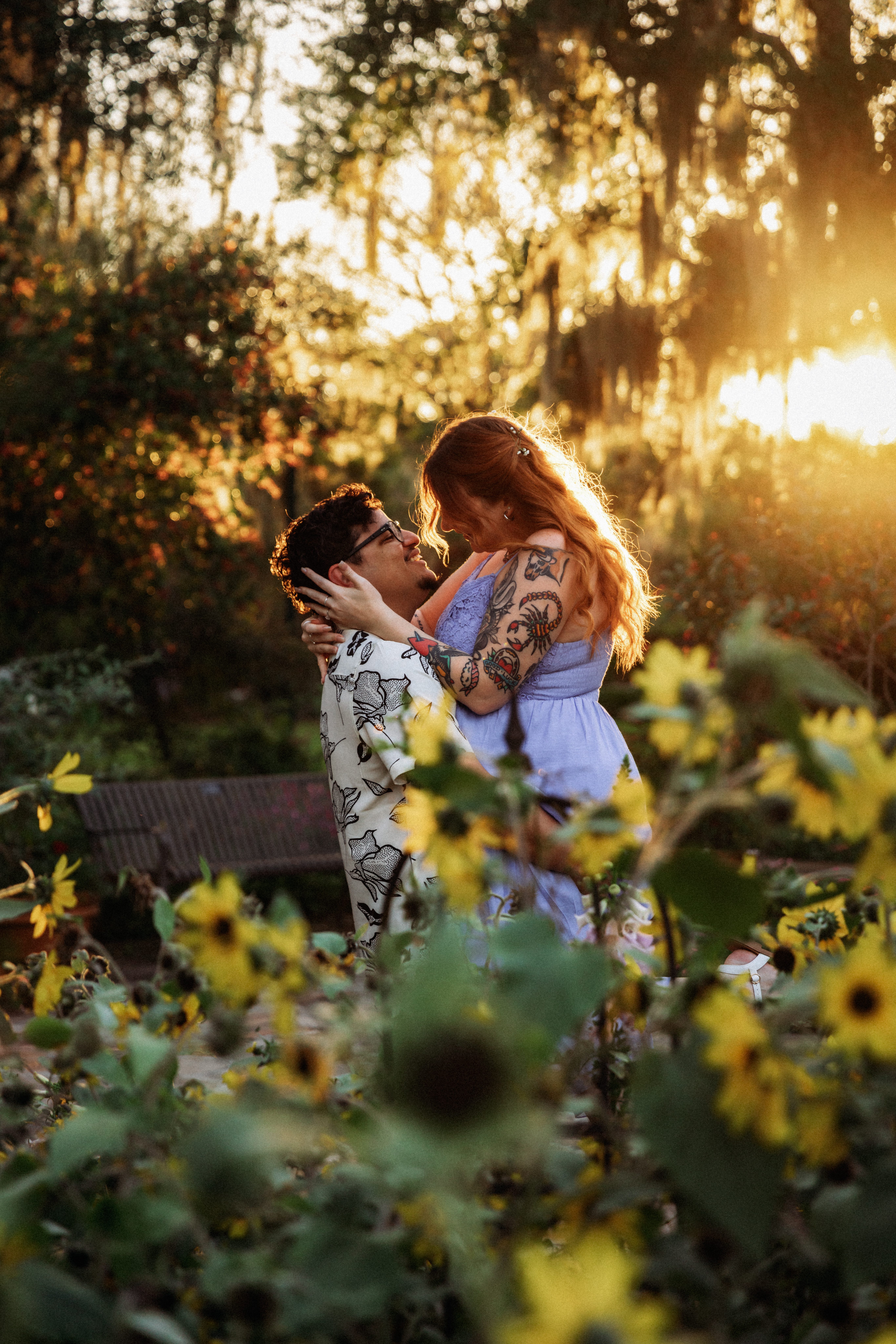An engaged couple embraces among sunflowers at Harry P. Leu Gardens during golden hour, photographed by Orlando Engagement Photographer Shannon Lee.