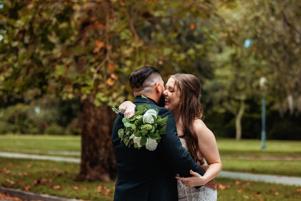 An engaged couple embraces and smiles in a lush setting at Mead Botanical Garden, photographed by Orlando Engagement Photographer Shannon Lee.