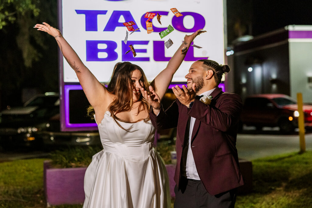 An engaged couple celebrates outside Taco Bell at night, tossing hot sauce packets in the air, photographed by Orlando Engagement Photographer Shannon Lee.