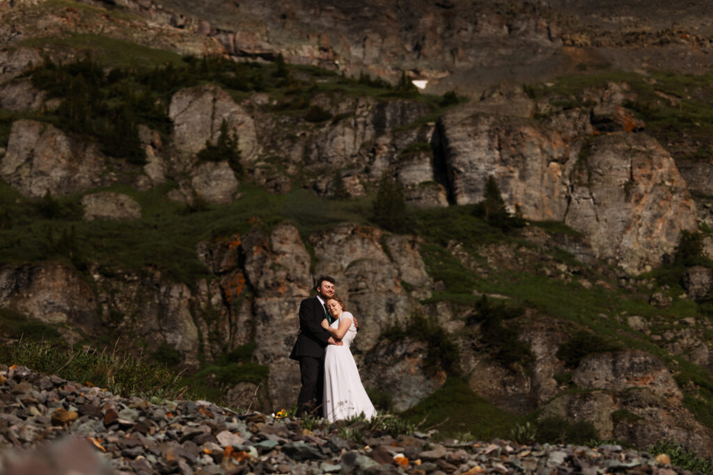 A couple embraces among the rugged rocky cliffs for their San Juans Mountain Elopement in Colorado.