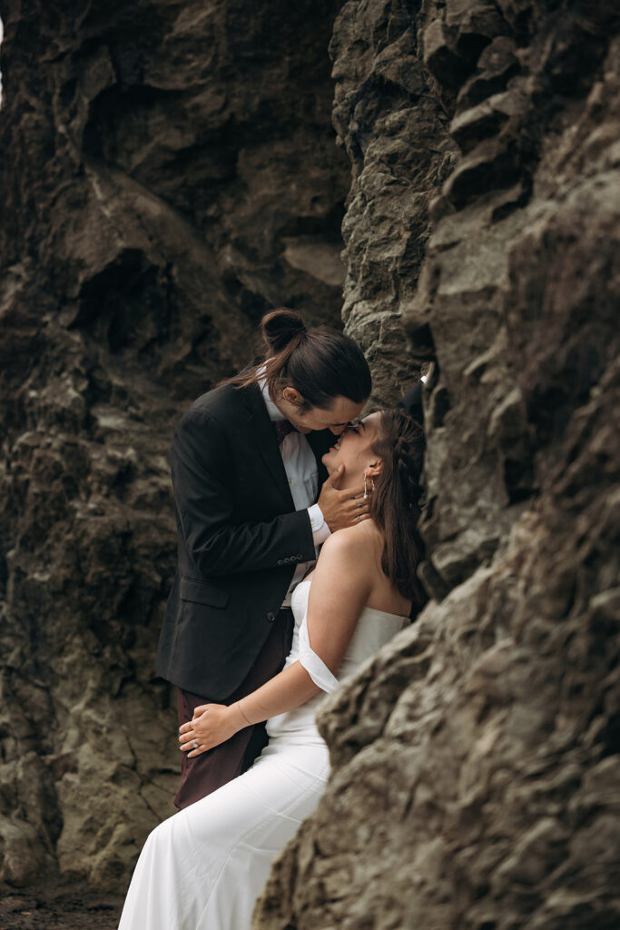 Couple kissing tucked between sea cave rocks during Ruby Beach Elopement, Olympic National Park, Washington