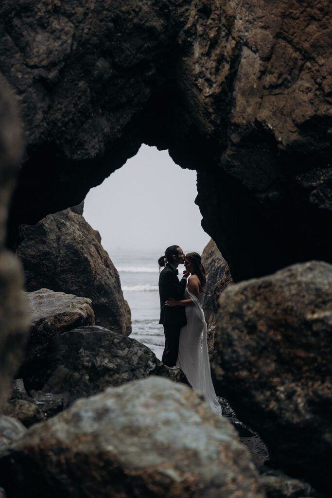 Couple embracing inside sea arch overlooking ocean during Ruby Beach Elopement, Olympic National Park, Washington