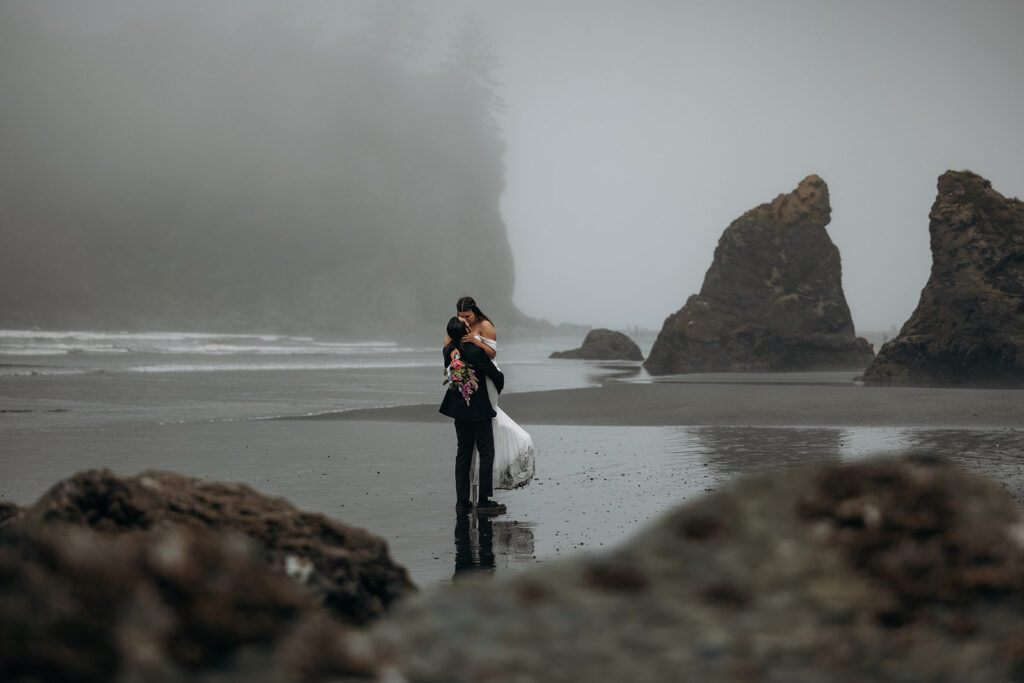 Groom lifting bride on foggy shoreline during Ruby Beach Elopement, Olympic National Park, Washington