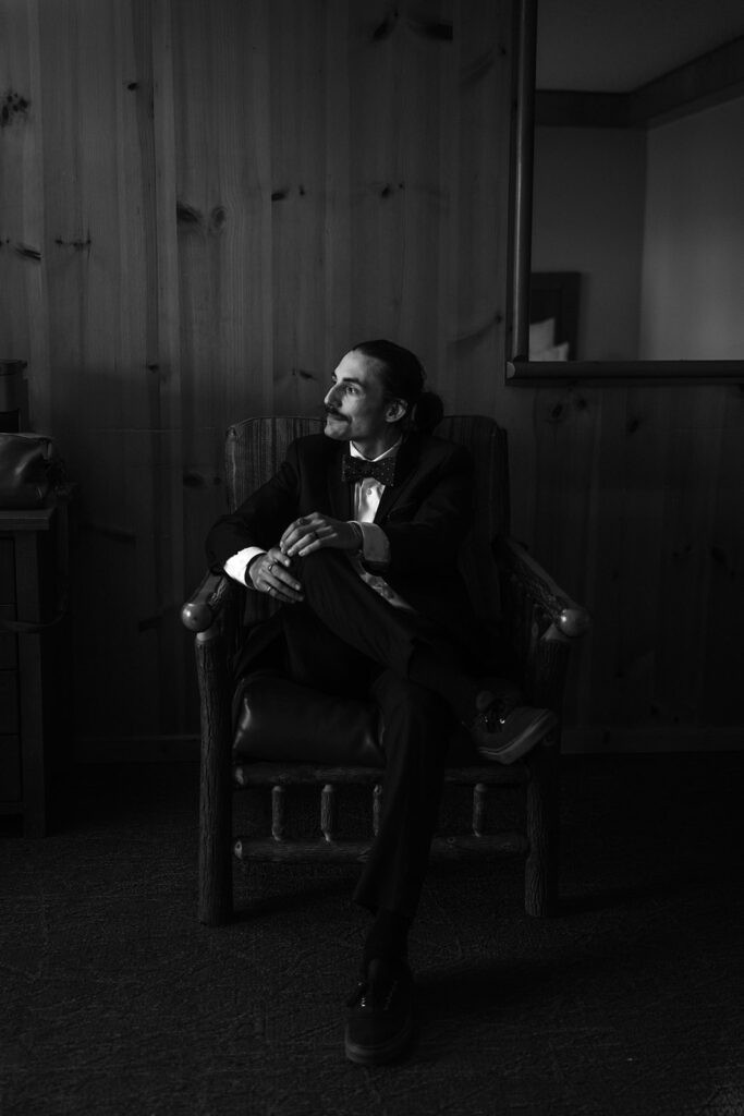 Groom seated in wooden chair getting ready at Kalaloch Lodge for Ruby Beach Elopement, Olympic National Park, Washington