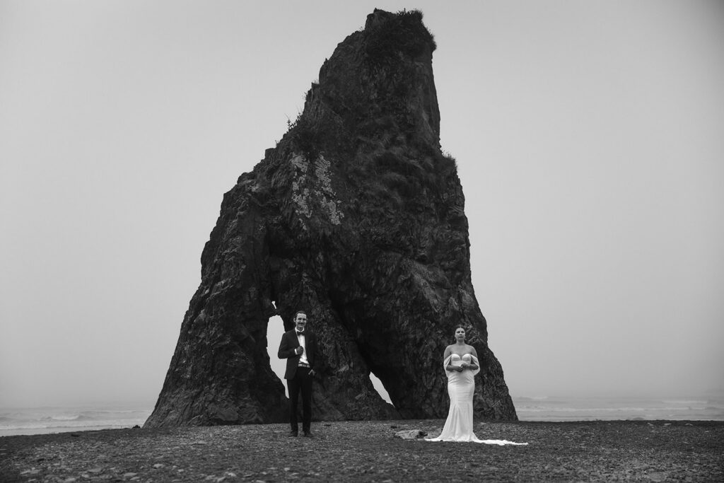 Bride and groom beneath towering sea stack during Ruby Beach Elopement, Olympic National Park, Washington